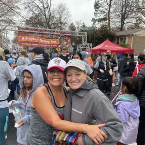 Two women at the Arlington Turkey Trot smile for the camera
