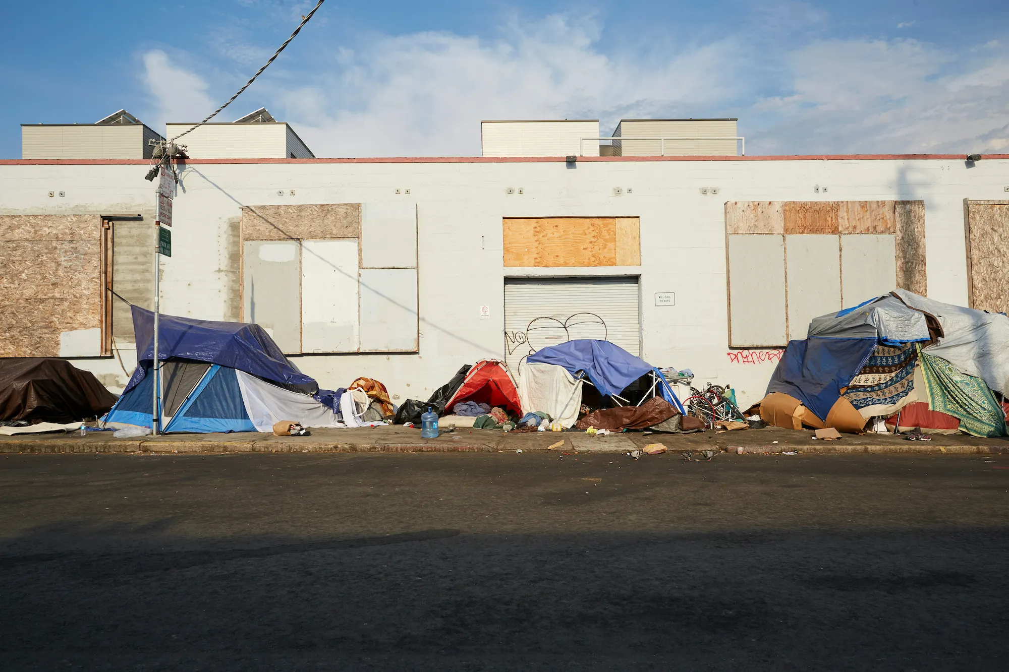 Tents and belongings in a line on a sidewalk outside of a building